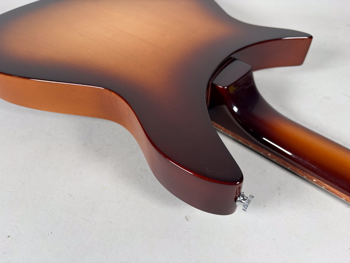 The guitar's Montezuma Brown sunburst back and neck are shown from the lower bout, with a chrome strap button visible.