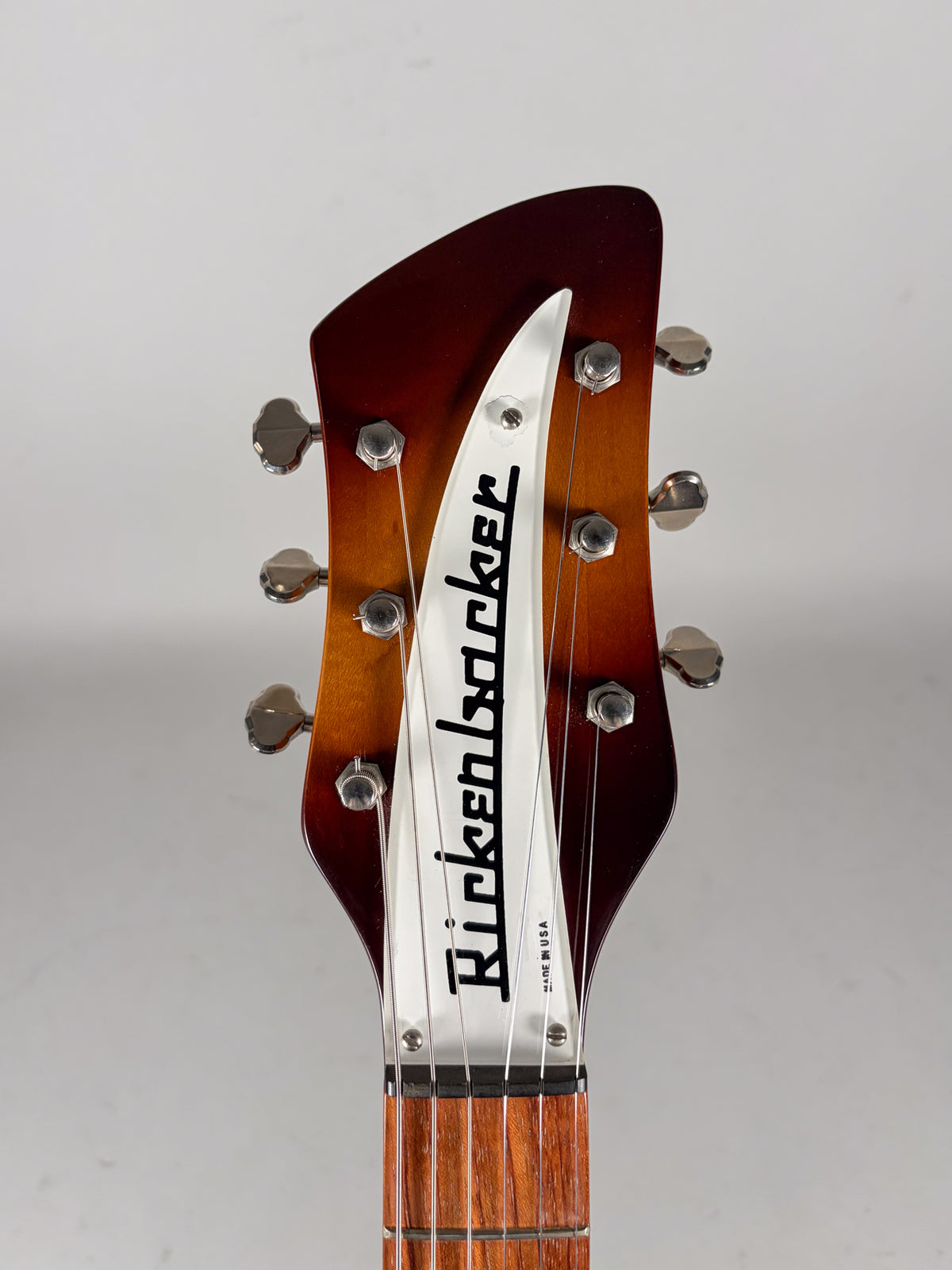 The guitar's Montezuma Brown headstock, with a white truss rod cover, six chrome tuners, and a dark fretboard.