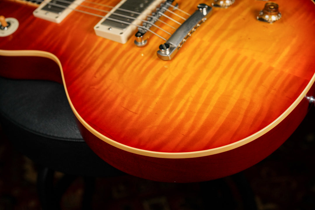 Close-up of the guitar's lower bout, showing the sunburst finish with flame maple top, cream binding, and light surface wear.