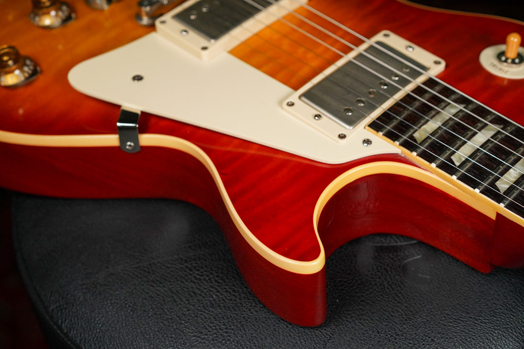 Close-up of the lower bout of a sunburst Les Paul, showing the flame maple top, cream binding, and two humbuckers.