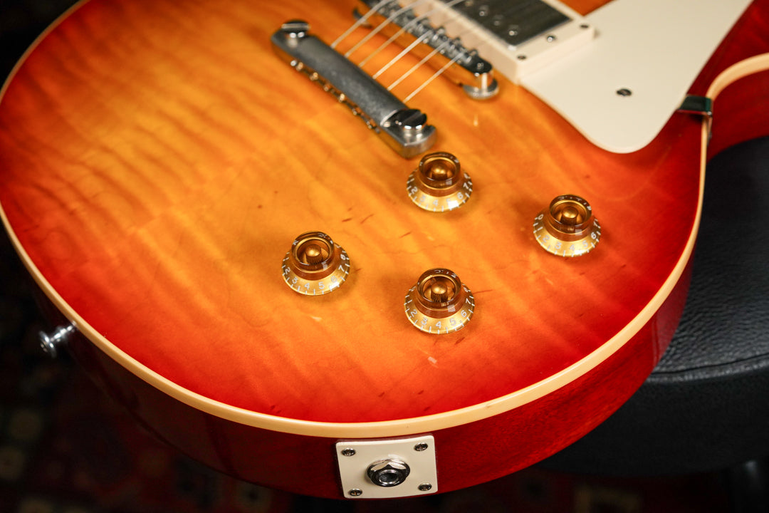 Close-up of the sunburst body with flame maple top, showing four amber top hat knobs, output jack, and light wear.