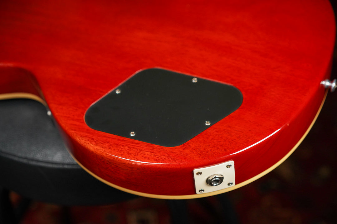 The lower bout of the guitar's cherry sunburst back, showing the black control cavity cover and the output jack plate.