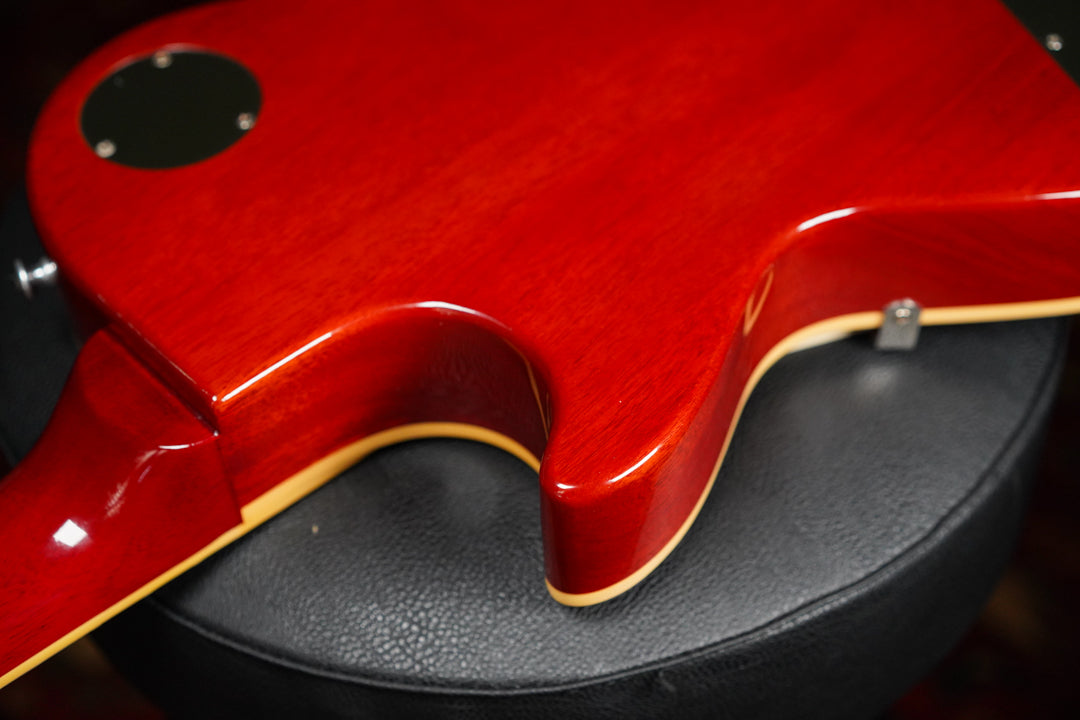 The back of the guitar's cherry sunburst body, showing the neck joint and control cavity cover, with light binding.