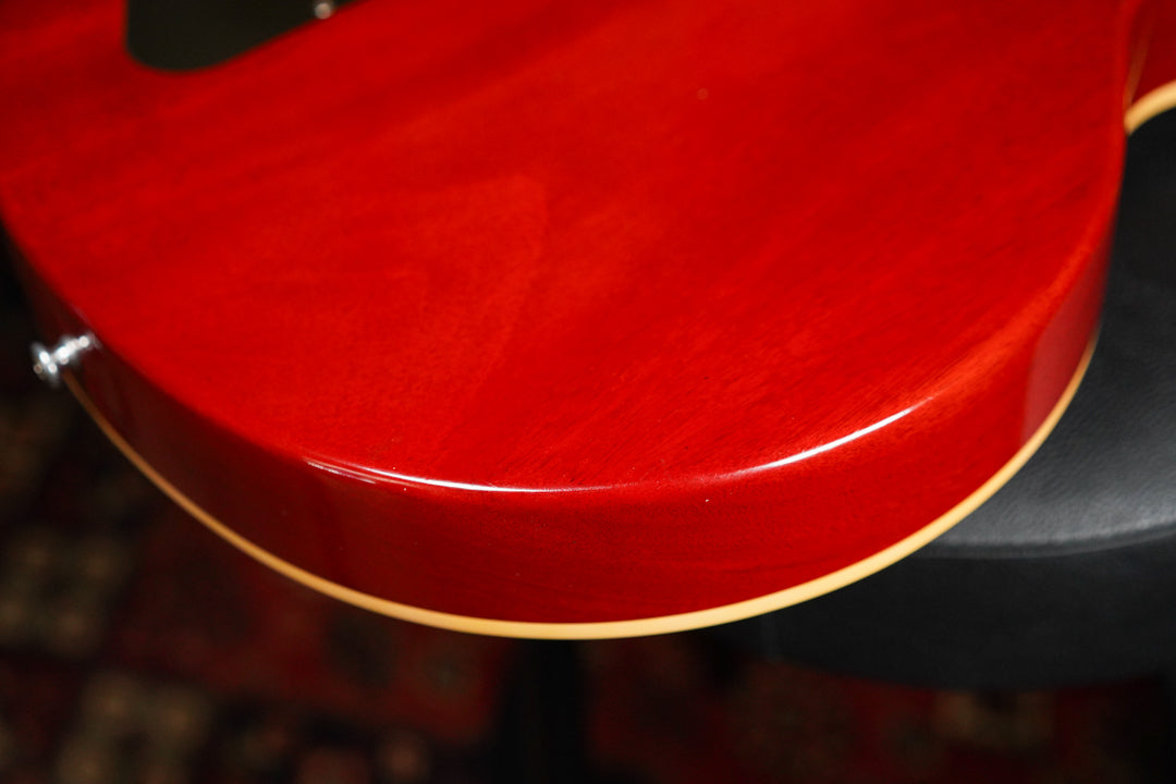 Close-up of the guitar's lower bout, showing the glossy cherry sunburst finish, cream binding, and a strap button.