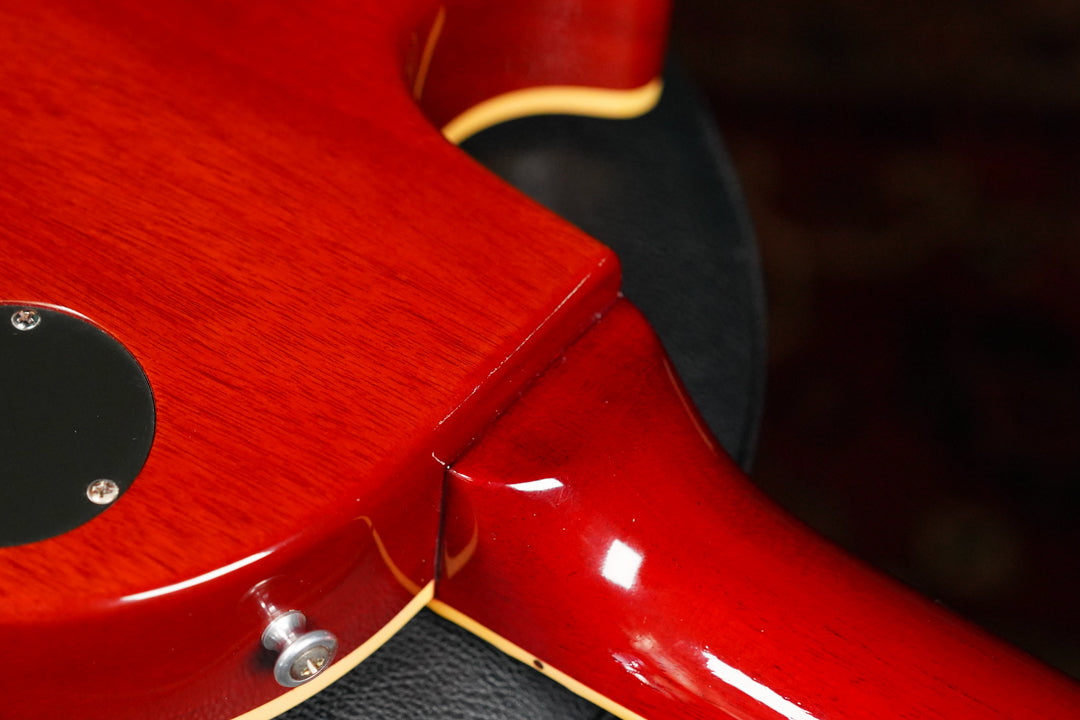 Close-up of the guitar's back, showing the cherry sunburst finish, neck joint, strap button, and a black control cavity cover.