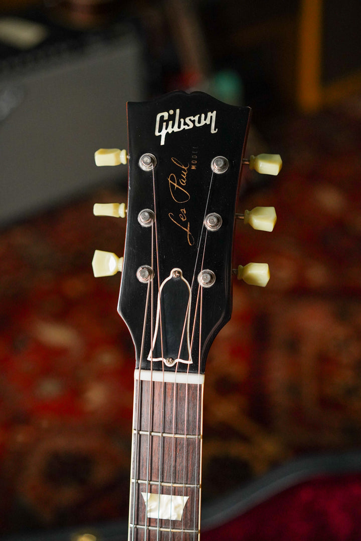 The guitar's black headstock with cream tuners and dark rosewood fretboard with trapezoid inlays is shown from above.