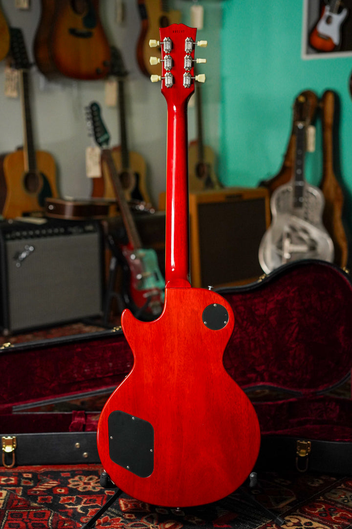 The back of a cherry red Les Paul with a glossy finish, showing the headstock, neck, and body with two black control plates.