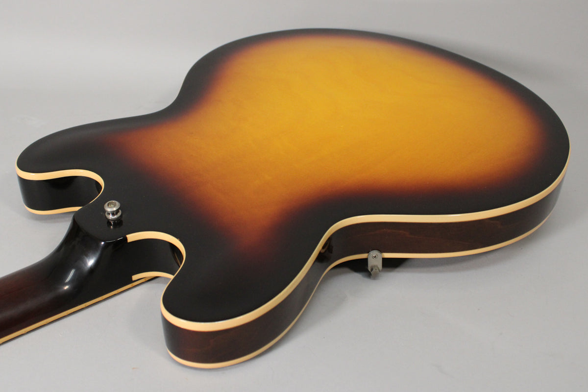 The back of the sunburst semi-hollow guitar, showing the neck joint, output jack, and strap button, with light finish checking.