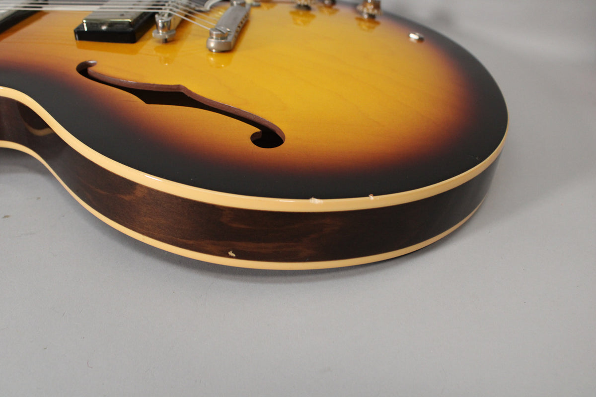 Close-up of the sunburst body's lower bout, showing the f-hole, binding, and two small chips on the dark brown side.