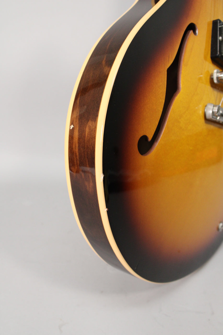 Close-up of the sunburst guitar's lower bout, showing the F-hole, body binding, and several small chips on the side.