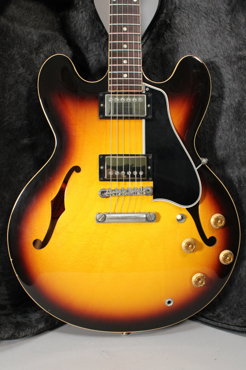 Full-frame view of a sunburst semi-hollowbody electric guitar with f-holes, two humbuckers, and four gold top hat knobs.