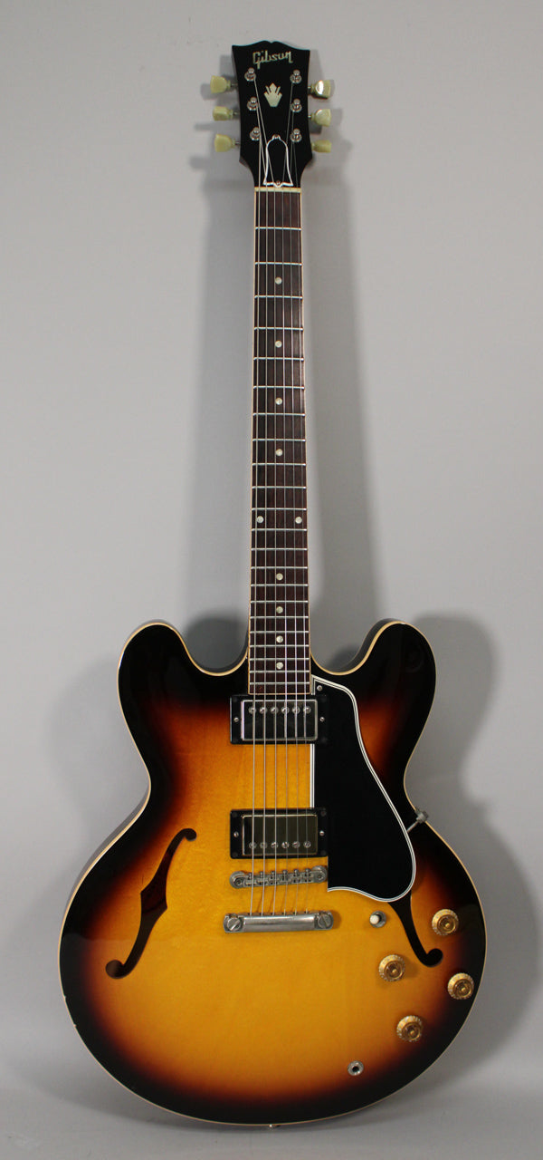 Full front view of a sunburst semi-hollowbody electric guitar with two humbuckers, a black pickguard, and four gold control knobs.
