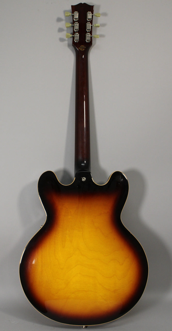 The guitar's back, headstock to lower bout, shows a glossy sunburst finish with light checking and six cream-button tuners.