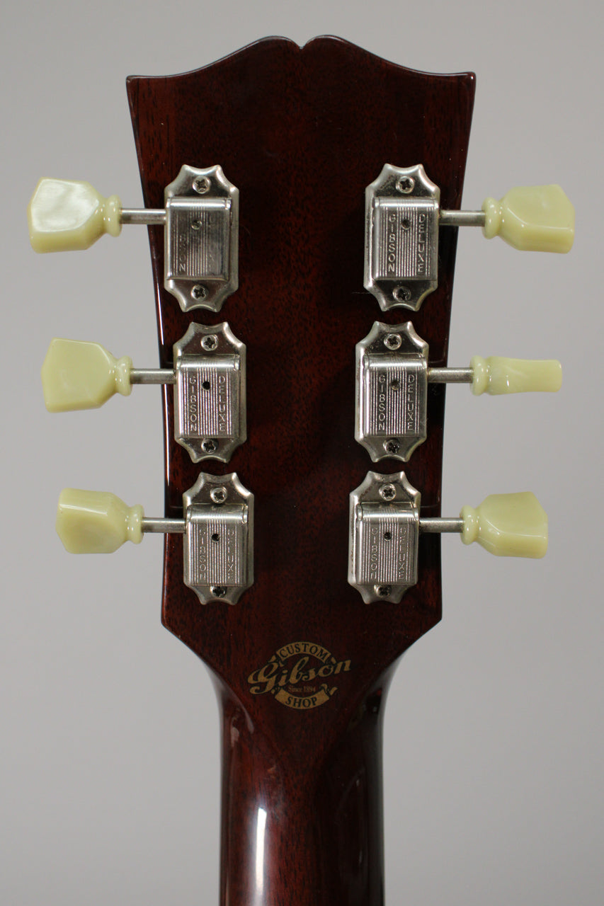 The back of a dark cherry headstock with six cream tuning pegs and chrome tuners, showing light wear.