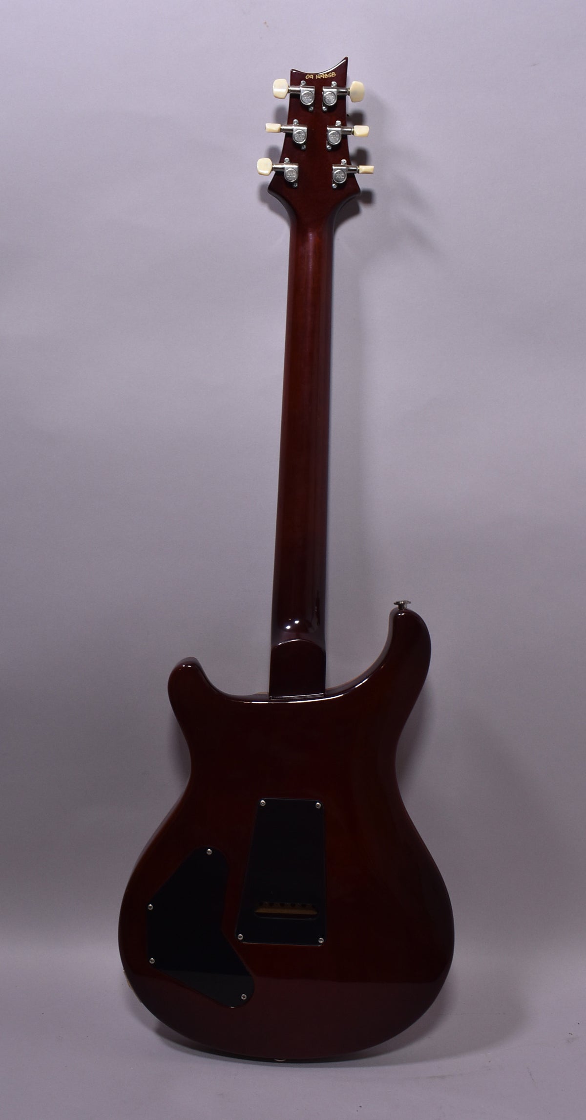 The guitar's back is dark cherry sunburst, with two black control cavity covers and six cream-button tuners on the headstock.