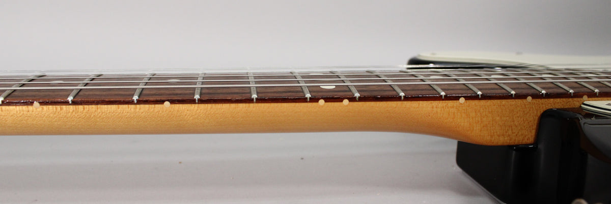 Close-up of the guitar's maple neck and dark fretboard, showing white dot inlays and light fret wear.