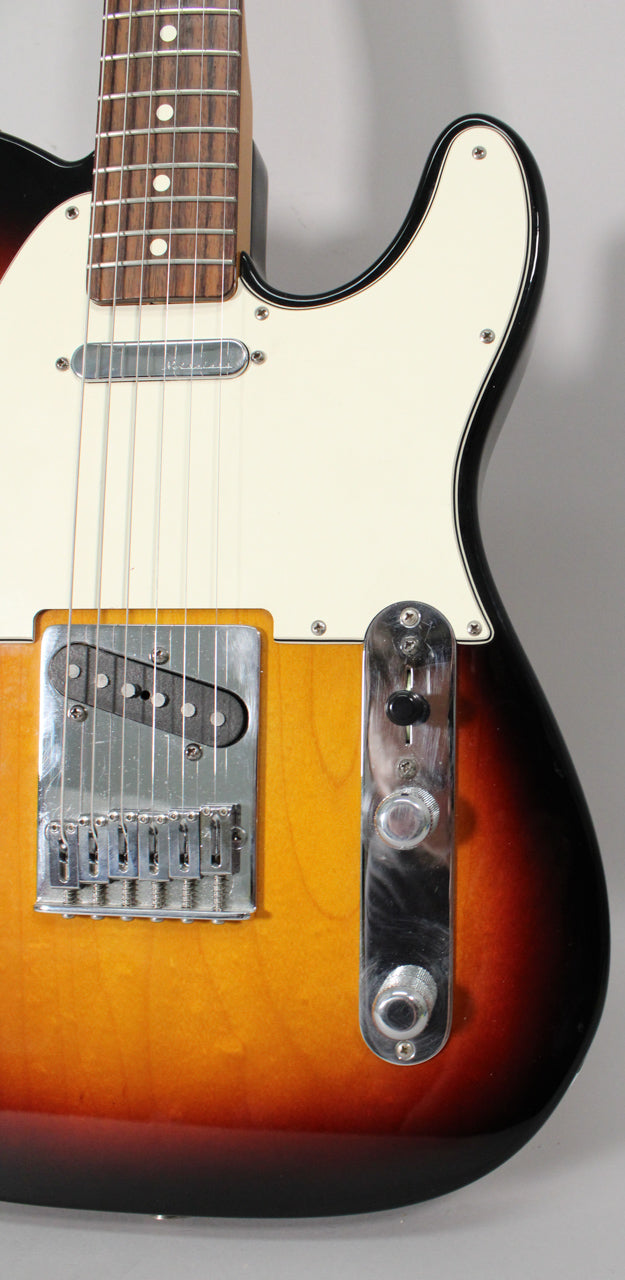 Close-up of a sunburst Telecaster body, showing the lower neck, white pickguard, chrome bridge, and control plate with three knobs.