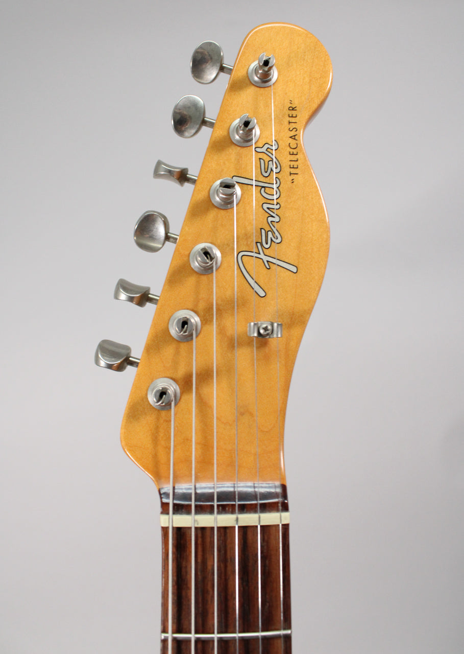 Close-up of the guitar's headstock, angled slightly left, showing six silver tuners, a string tree, and a dark rosewood fretboard.