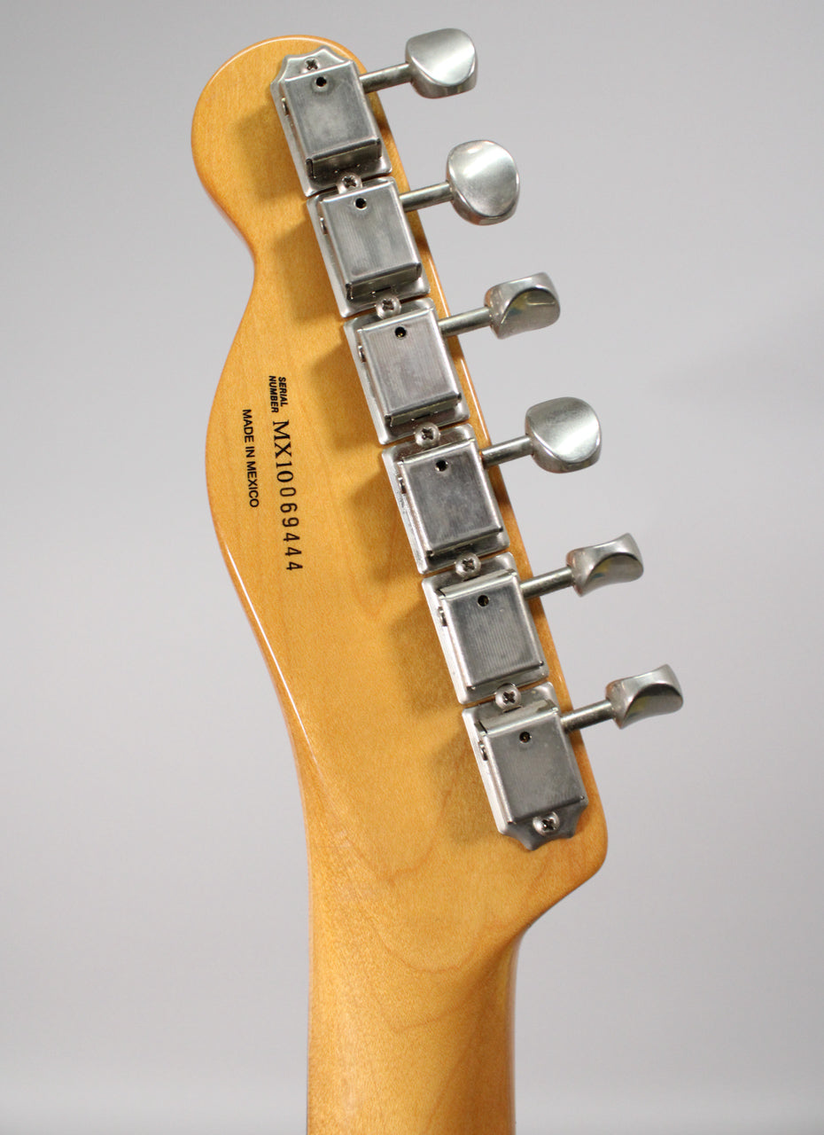 The back of a light maple headstock and neck, showing six brushed chrome tuners with oval buttons.