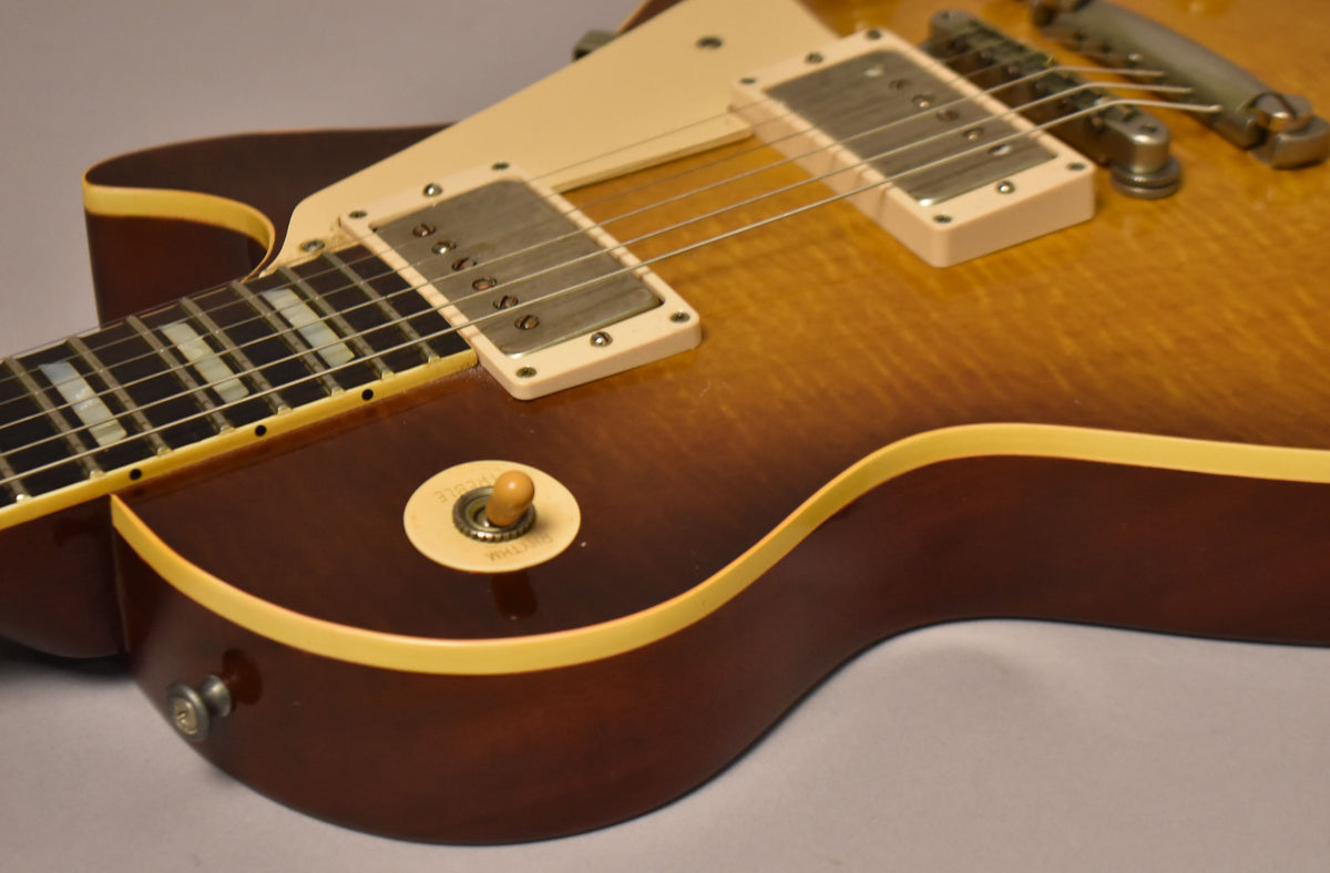 Close-up of the guitar's sunburst body, showing the neck, two humbuckers, cream binding, and a 3-way toggle switch.