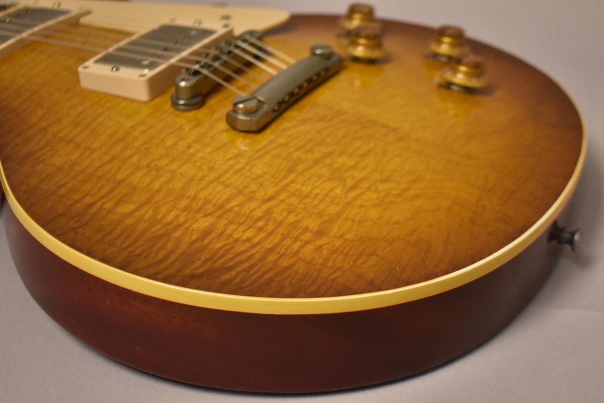 Close-up of the guitar's lower body, showing the flame maple sunburst top, cream binding, and dark brown sides, with aged nickel hardware.