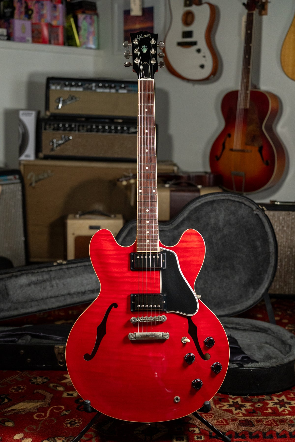 Full-body shot of a cherry red flamed maple semi-hollow guitar with black humbuckers, pickguard, and control knobs.
