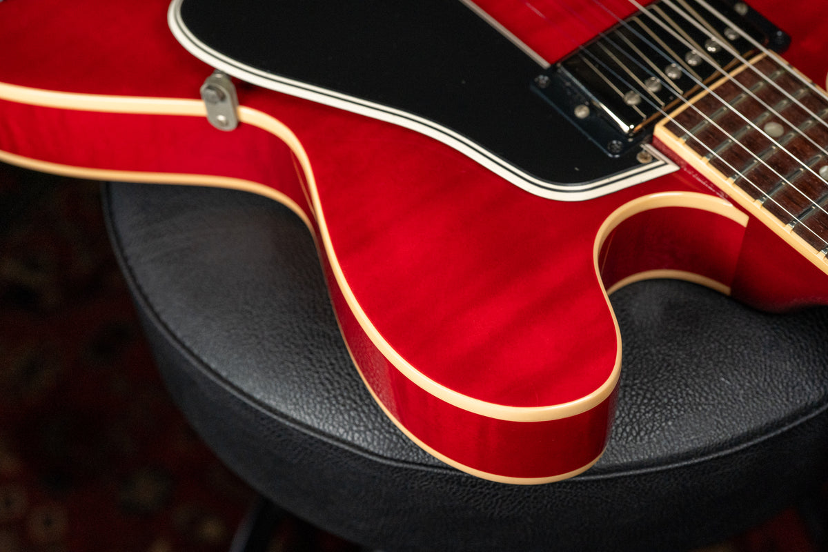 Close-up of the cherry red flamed maple body, showing the lower bout, black pickguard, neck pickup, and part of the fretboard.