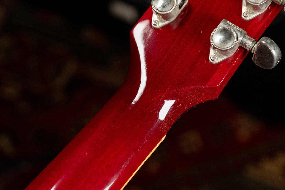 Close-up of the cherry red headstock and upper neck, showing light wear and three silver Grover tuners.