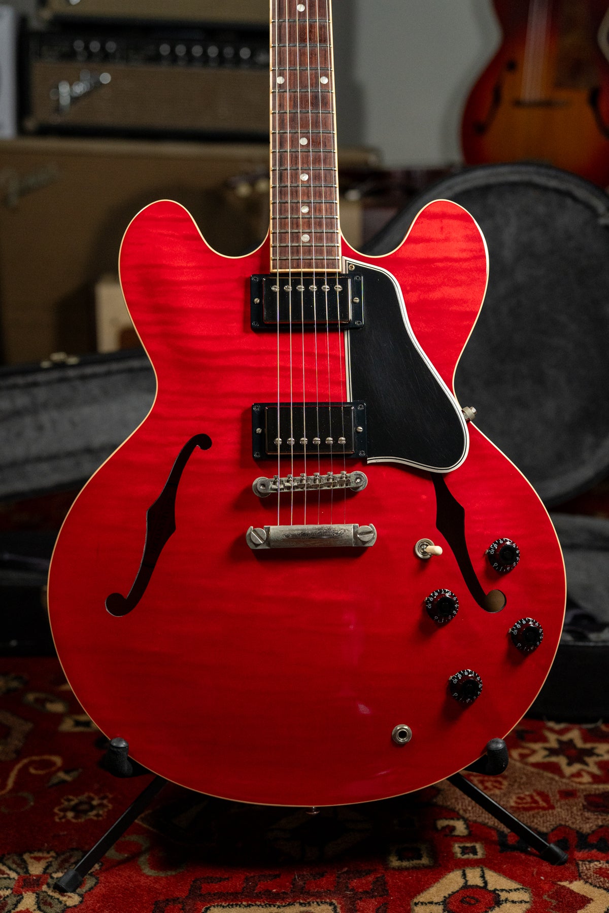 Cherry red flamed maple semi-hollow guitar, angled to show the body, f-holes, black pickguard, humbuckers, and control knobs.