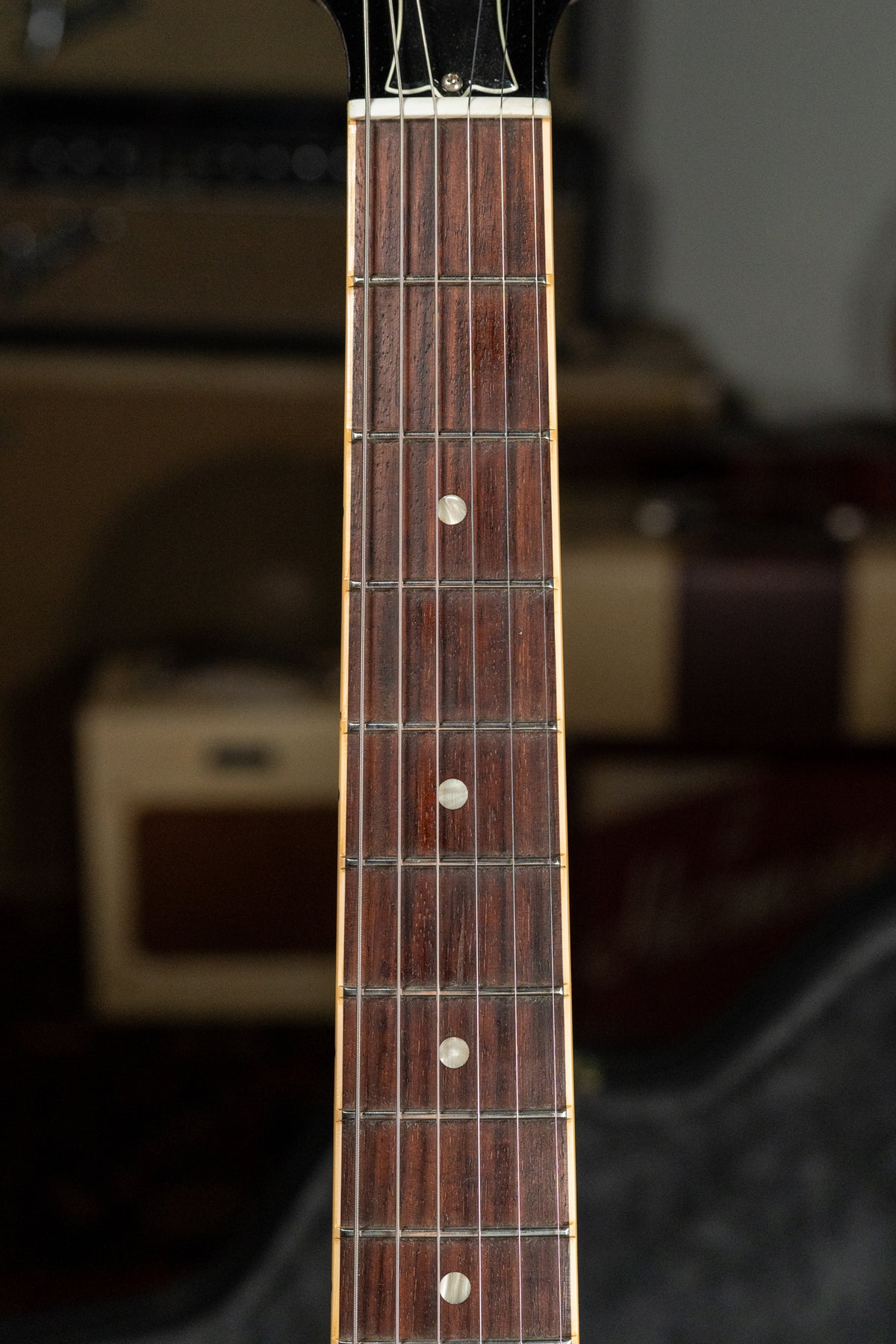 Close-up of the guitar's dark rosewood fretboard with dot inlays, showing light wear and a cream binding along the edge.