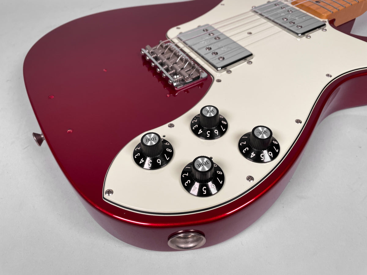 Close-up of the Candy Apple Red body and cream pickguard, showing four black control knobs, two humbuckers, and a chrome bridge.