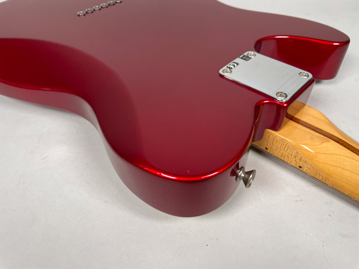 The guitar's candy apple red body, viewed from the back, shows a chrome neck plate and strap button, with a maple neck.