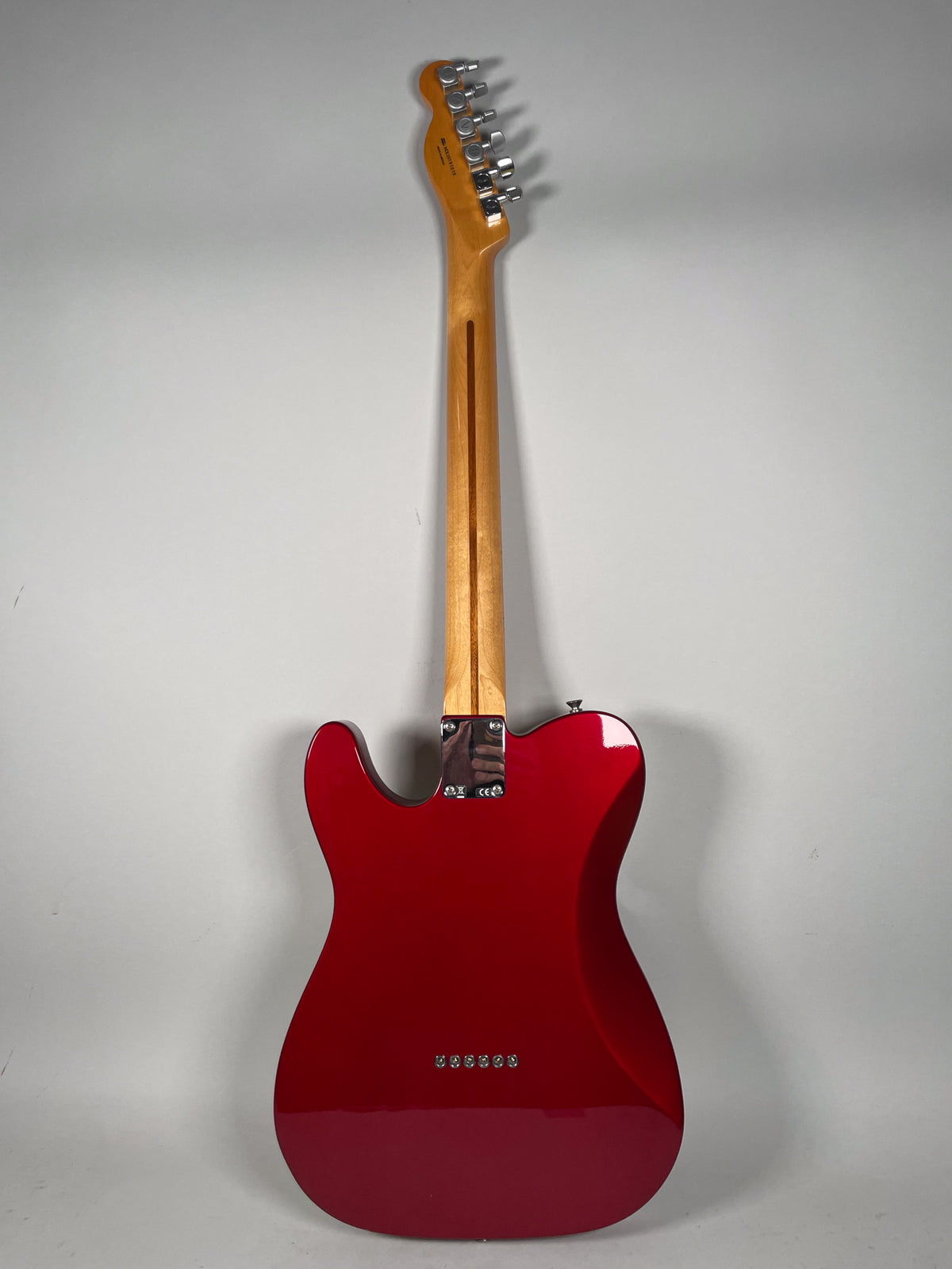 Full rear view of a glossy Candy Apple Red Telecaster with a maple neck and chrome tuners, showing string-through-body ferrules.