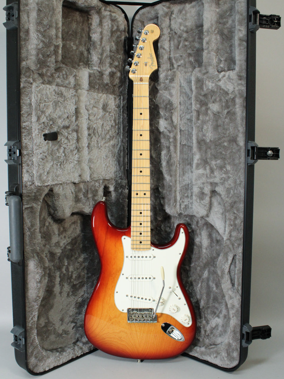 Full-length view of a Sienna Burst Stratocaster with a maple neck, white pickguard, three single-coil pickups, and tremolo bar, in a hard case.