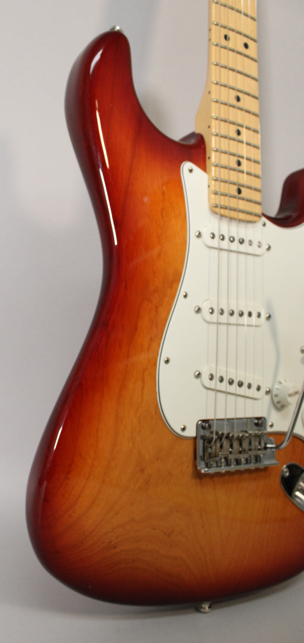 Upper body of a Sienna Burst Stratocaster, showing the maple neck, white pickguard, three single-coil pickups, and chrome tremolo bridge.