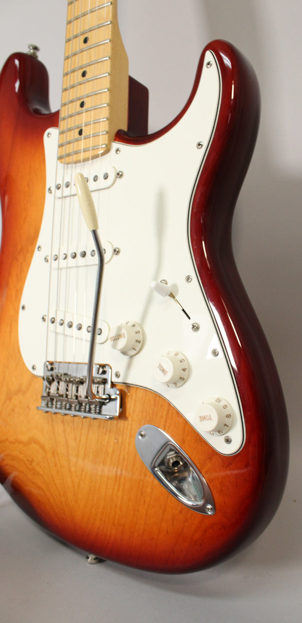 Close-up of a Sienna Burst Stratocaster body, showing the maple neck, white pickguard, chrome tremolo, and output jack.