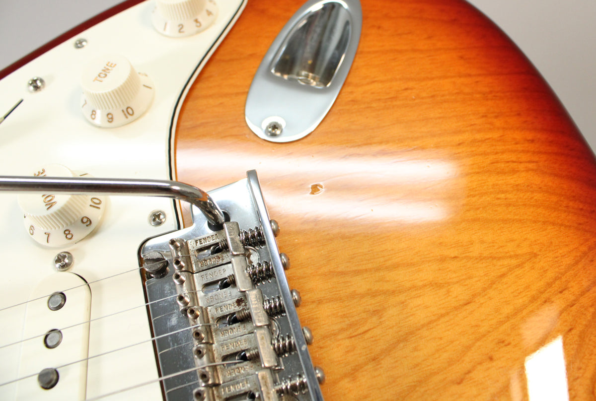 Close-up of the Sienna Burst body, showing the tremolo bridge, white pickguard, cream controls, and a small ding near the tremolo.