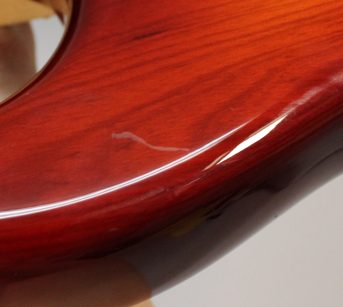 Close-up of the Sienna Burst guitar body, showing a white scuff mark and a small chip on the glossy finish near the edge.