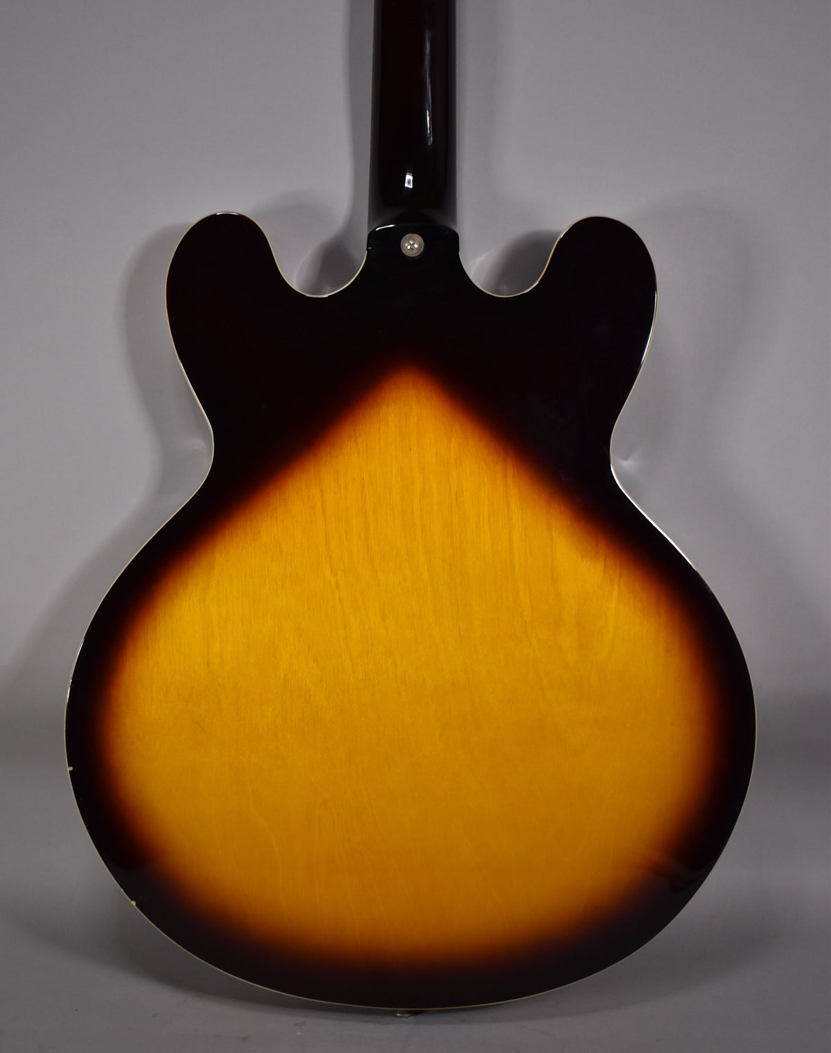 Rear view of a sunburst semi-hollow electric guitar, showing the body's dark edges fading to a bright amber center.