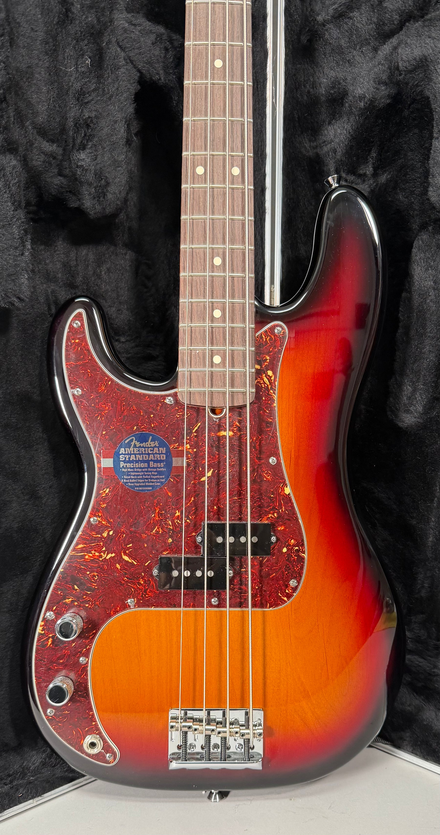 The bass is angled slightly, showing the sunburst body with a tortoiseshell pickguard, split-coil pickup, and chrome bridge.