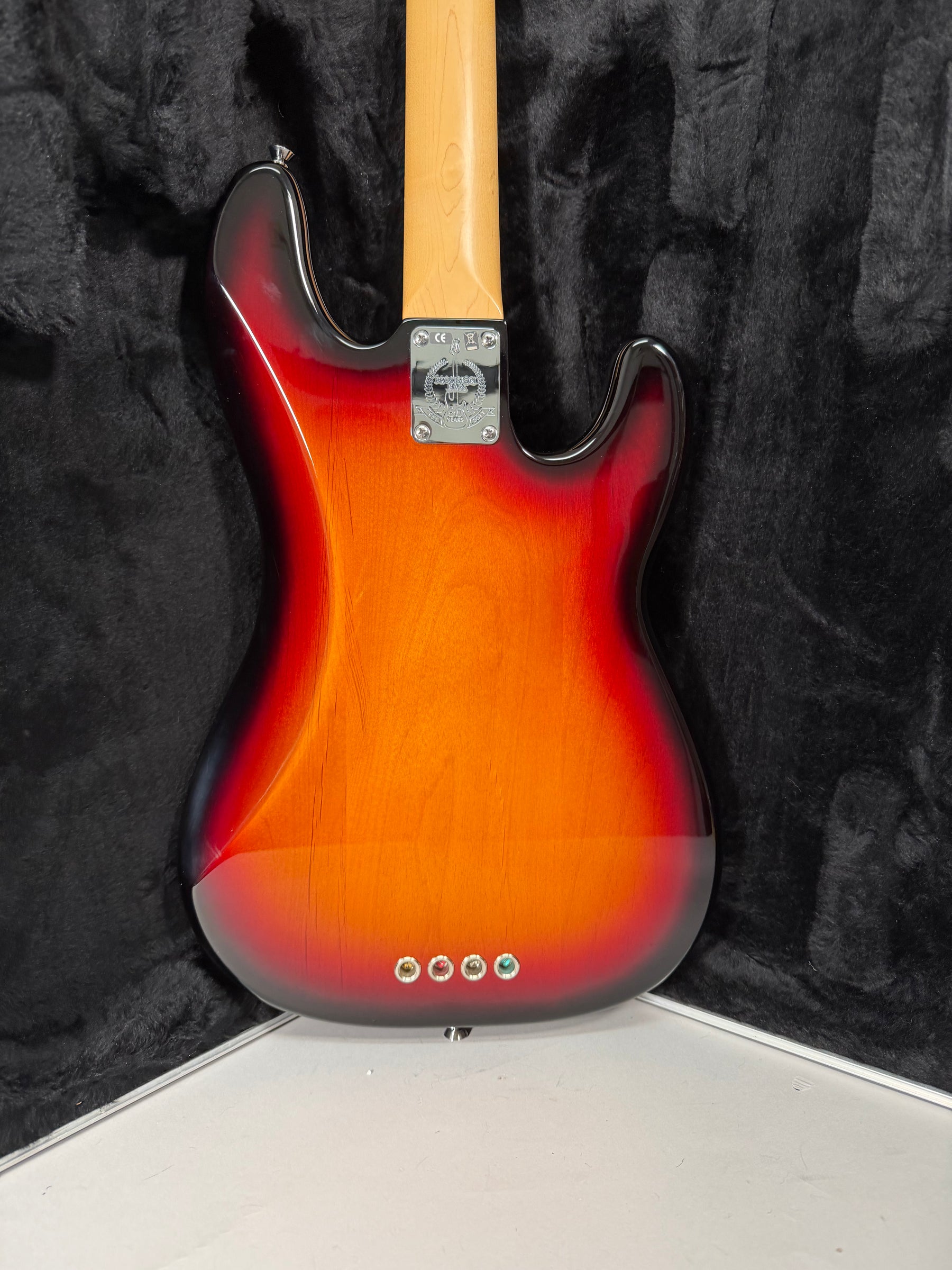 The bass's sunburst back shows a chrome neck plate, a light maple neck, and four string ferrules on the lower bout.