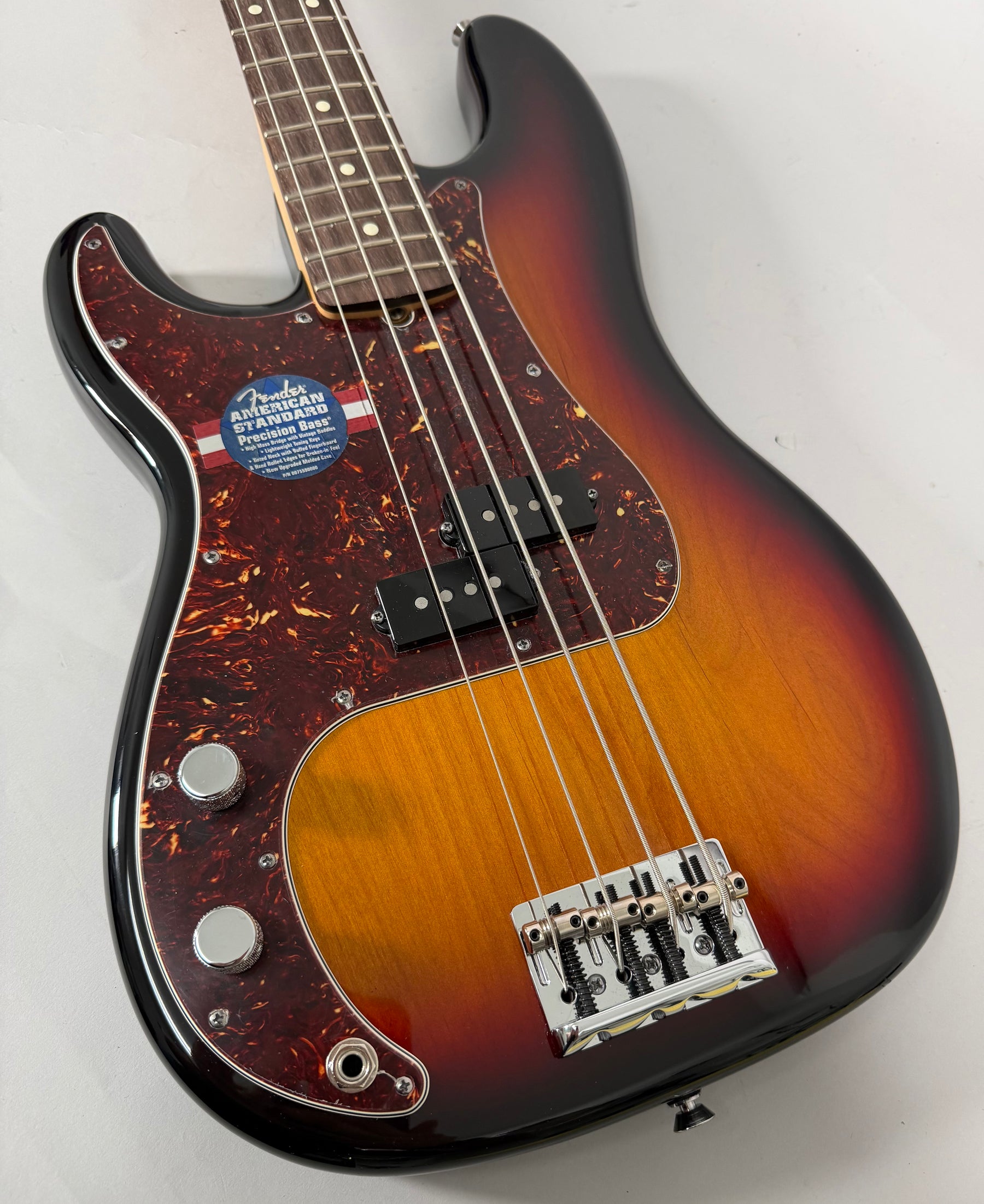 Left-handed sunburst bass, angled from above, showing the body, dark tortoiseshell pickguard, split pickup, and chrome bridge.