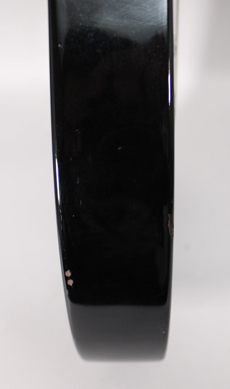 The black guitar body's lower bout edge shows two small paint chips and a larger area of chipped paint revealing brown wood.