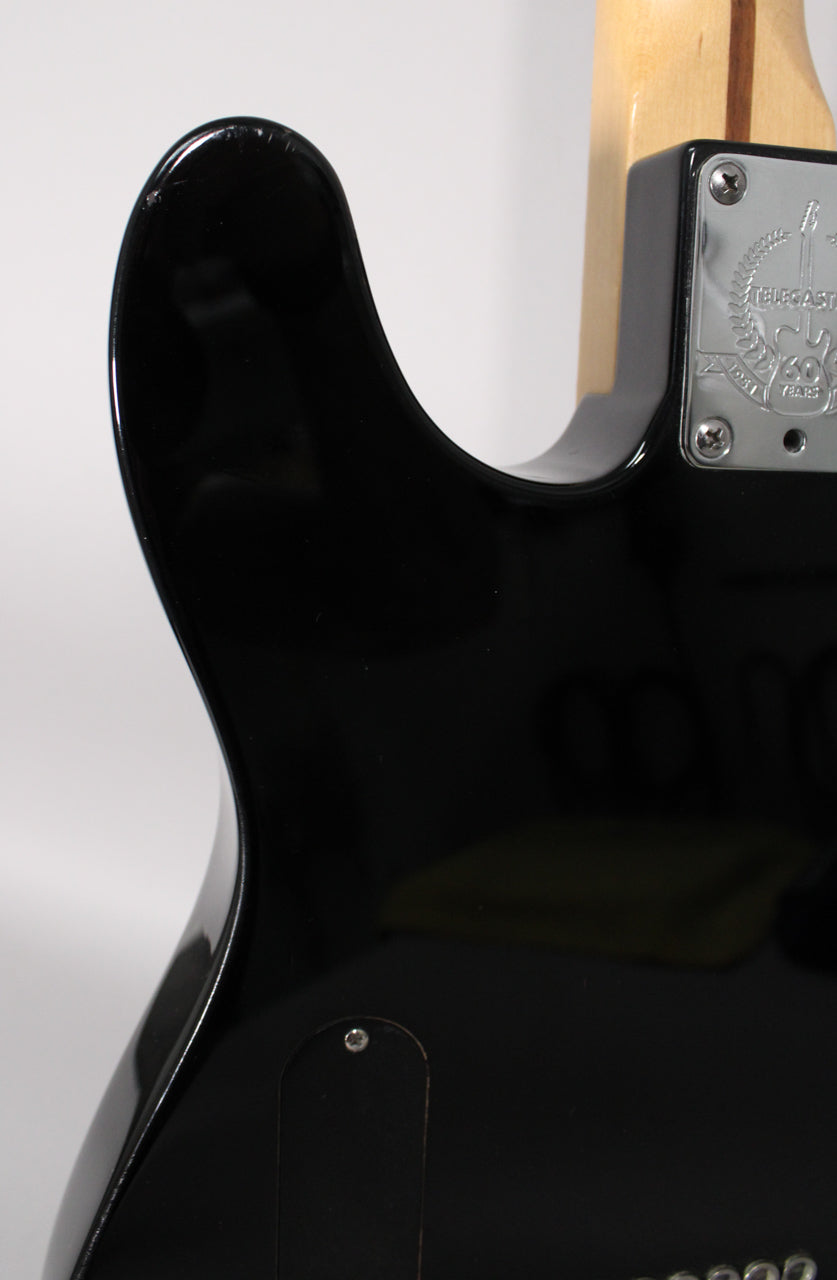 Close-up of the guitar's glossy black upper horn with a small chip, showing the neck plate and a black control cavity cover.