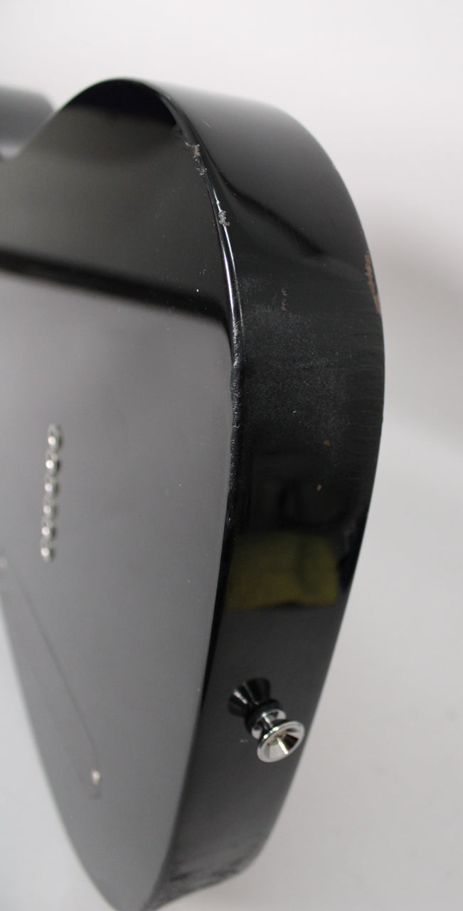 Close-up of the black guitar body's lower bout, showing finish wear and chips along the edge, with the output jack visible.