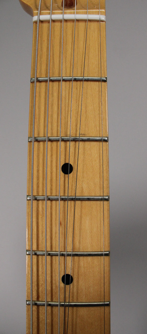 Close-up of the maple fretboard, showing the nut, frets, and black dot inlays on the 3rd, 5th, and 7th frets.