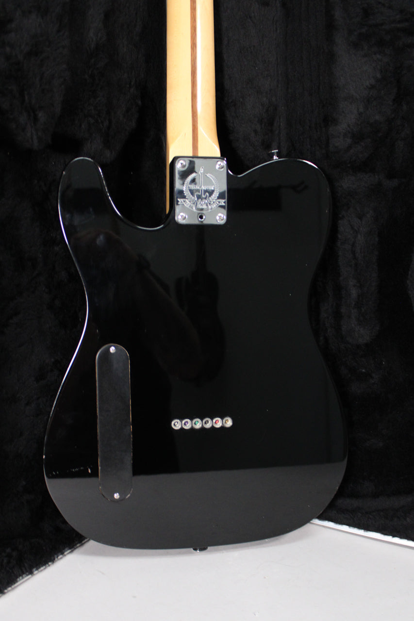 Rear view of a glossy black Telecaster body with a light maple neck, chrome neck plate, and six string-through-body ferrules.