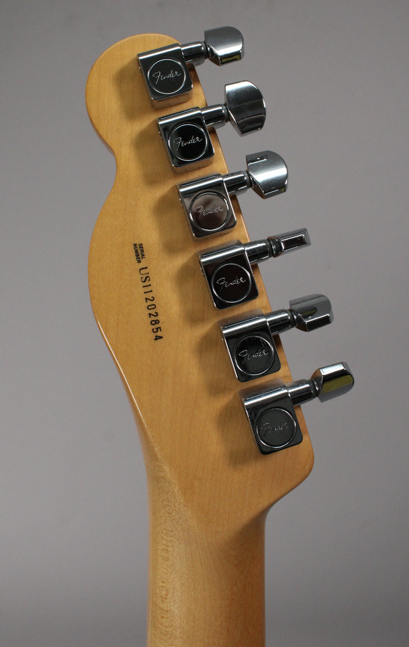 The back of the guitar's light wood headstock and neck, showing six chrome tuners and a serial number on the headstock.