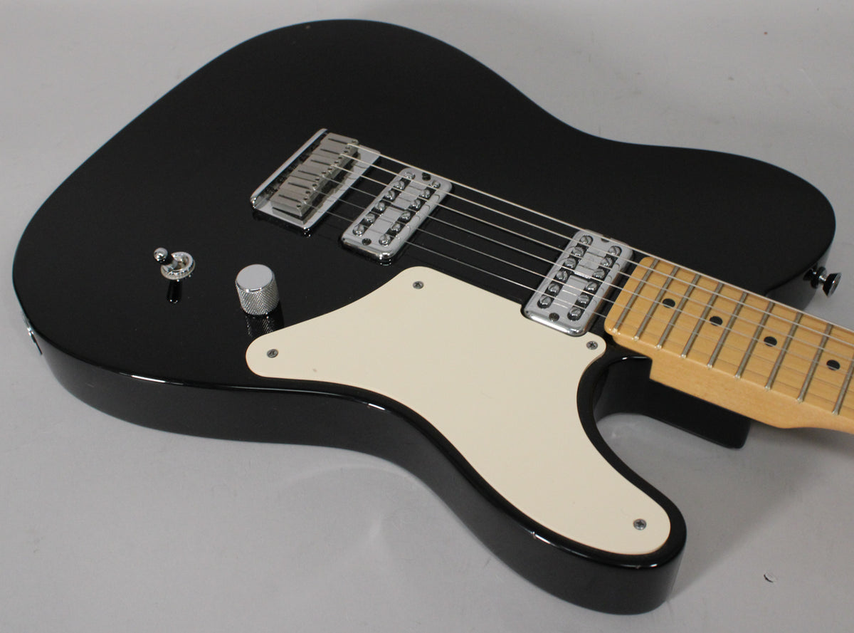 The black guitar body is angled, showing the cream pickguard, two chrome humbuckers, a knurled chrome knob, and a 3-way switch.