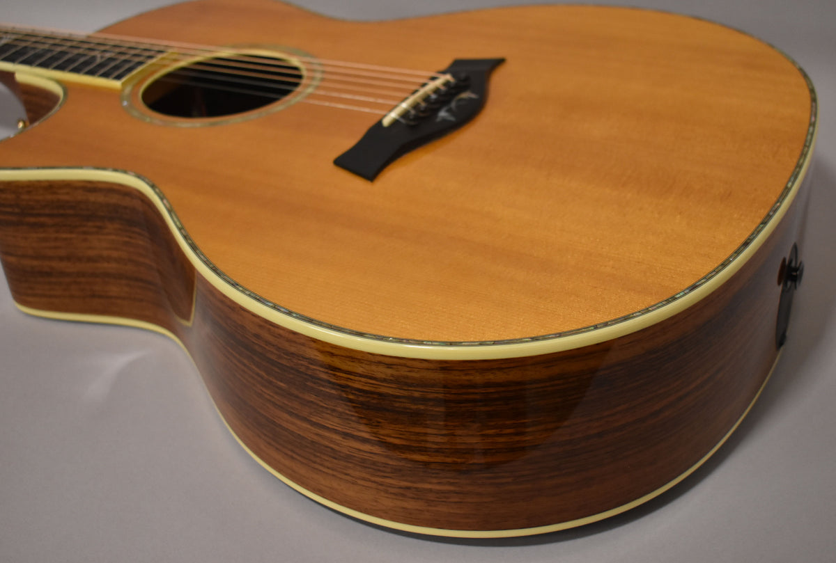 The lower bout of a natural finish acoustic guitar, showing the dark wood grain sides, light top, and cream binding.